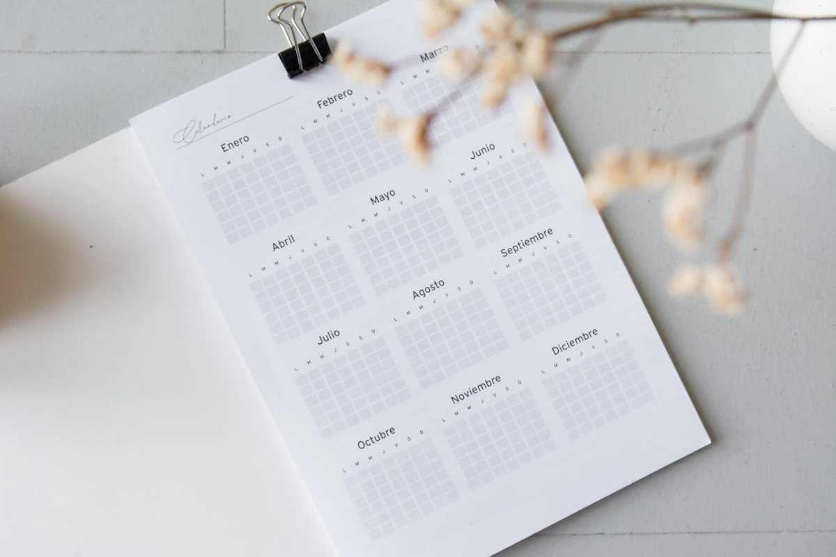 Calendario laboral anual impreso en español con los doce meses del año sobre una mesa blanca