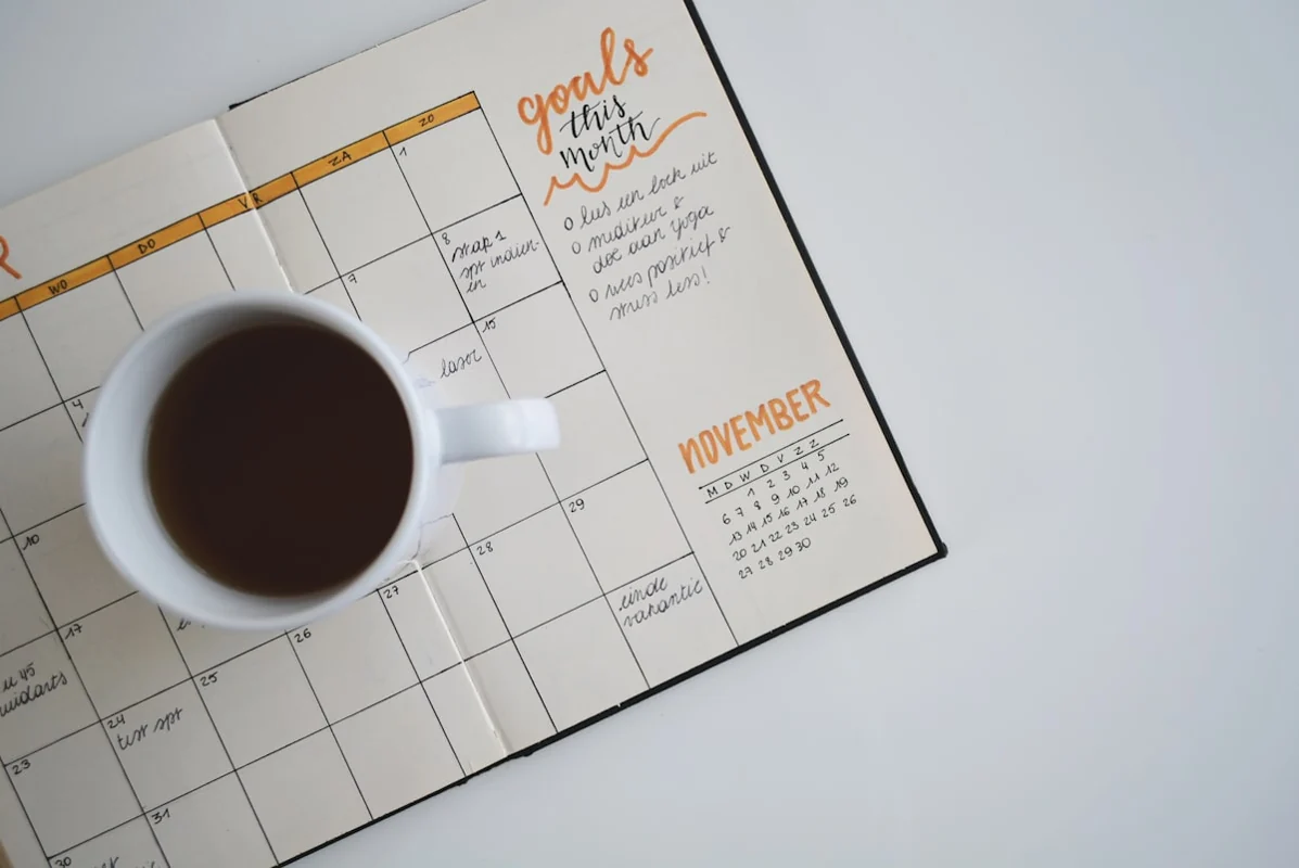 Calendario abierto sobre un escritorio junto a una taza de café