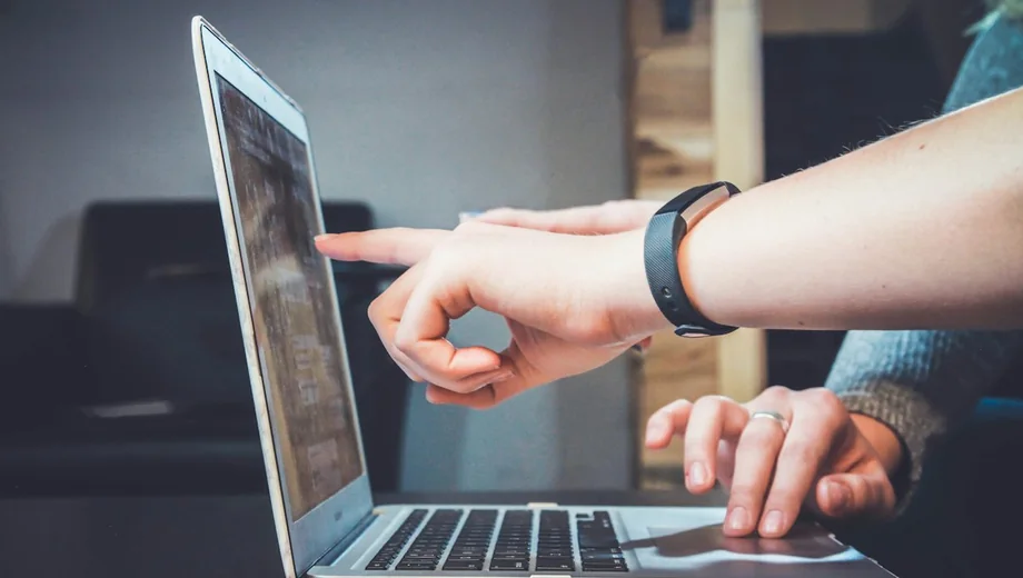 Dos personas señalando información en una computadora portátil