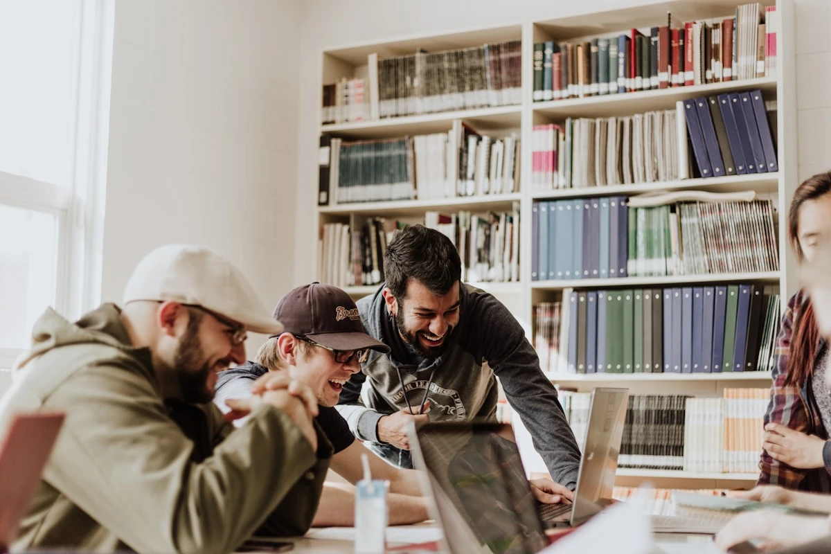 Estudiantes de formación profesional trabajando juntos con portátiles y archivadores en una biblioteca