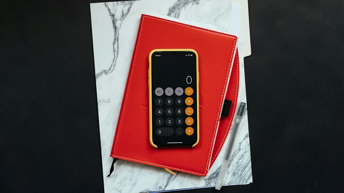 Calculadora, cuaderno y bolígrafo sobre una carpeta de documentos