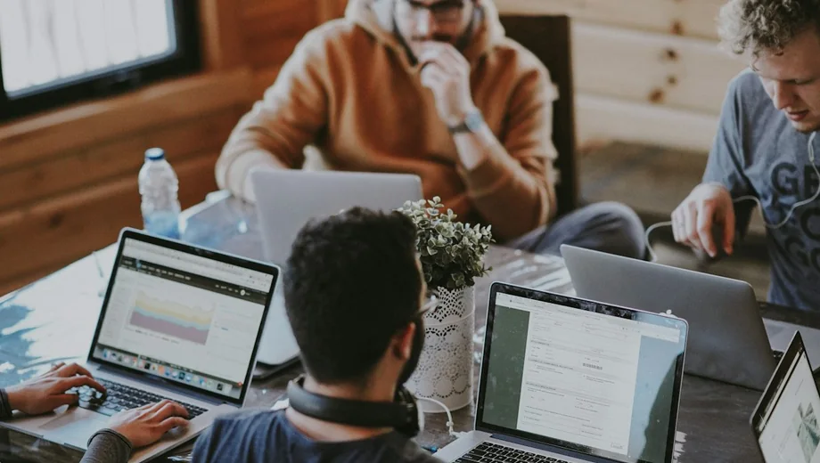 Personas trabajando con computadoras y revisando documentación