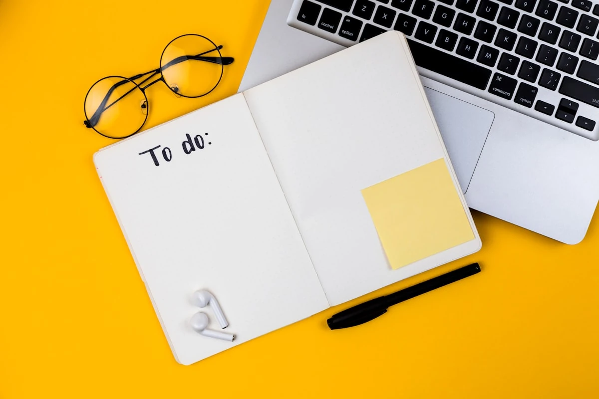 Cuaderno con una lista de tareas junto a una laptop para planificar el portafolio de un trabajo remoto sin experiencia