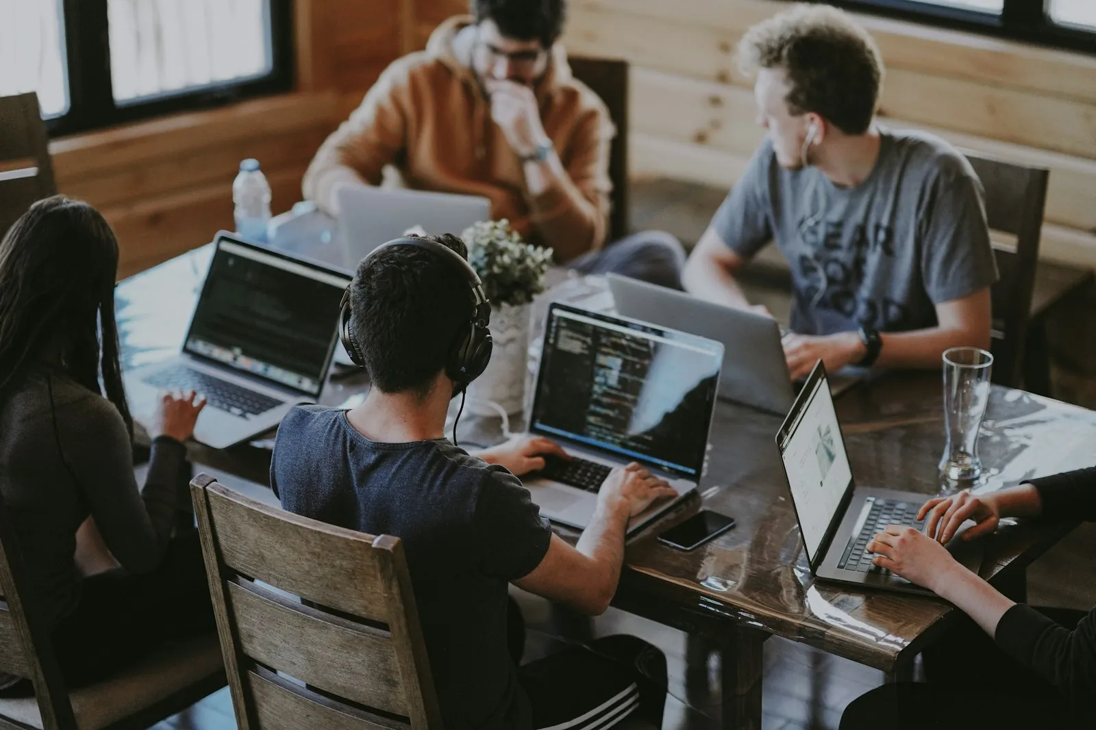 Equipo de personas trabajando con laptops alrededor de una mesa en una oficina informal