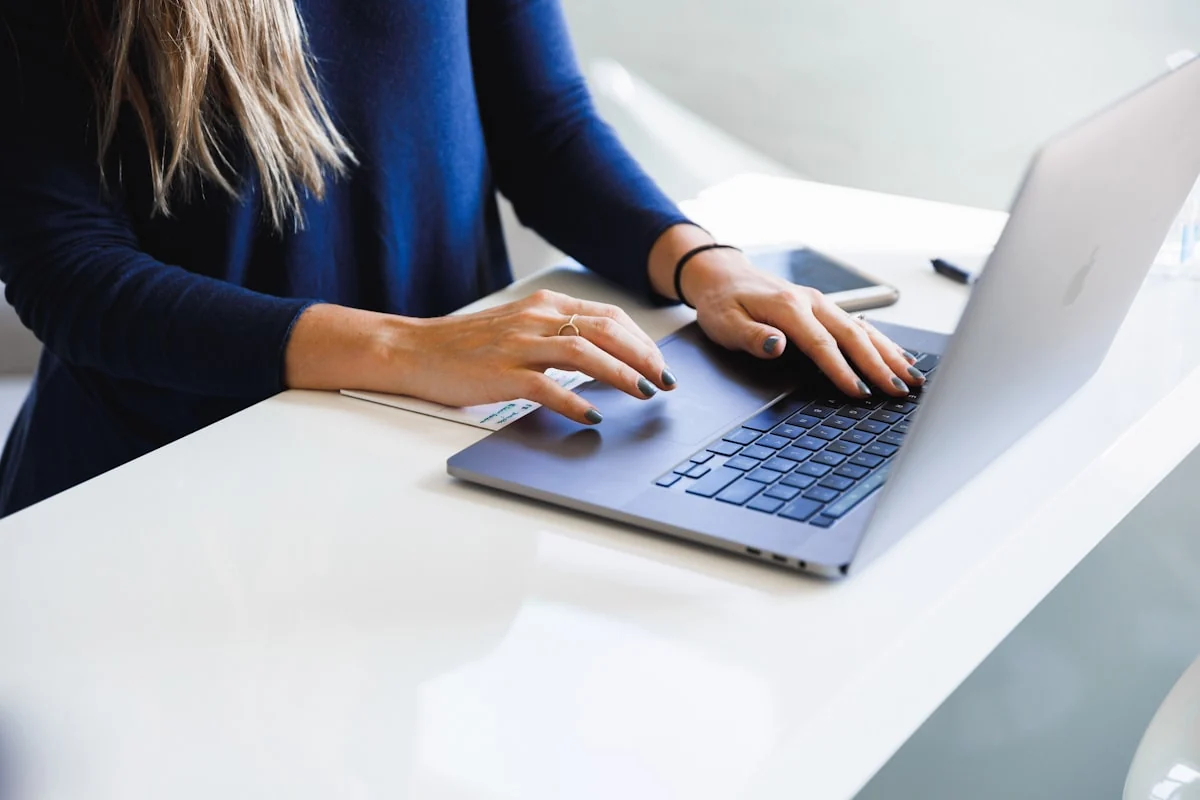 Persona editando su perfil profesional en un portátil sobre un escritorio blanco