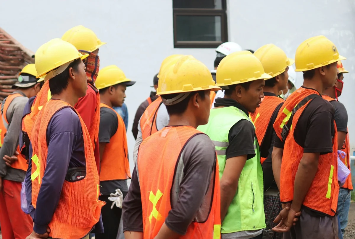 Grupo de trabajadores con casco y chaleco reflectante durante una charla en una obra